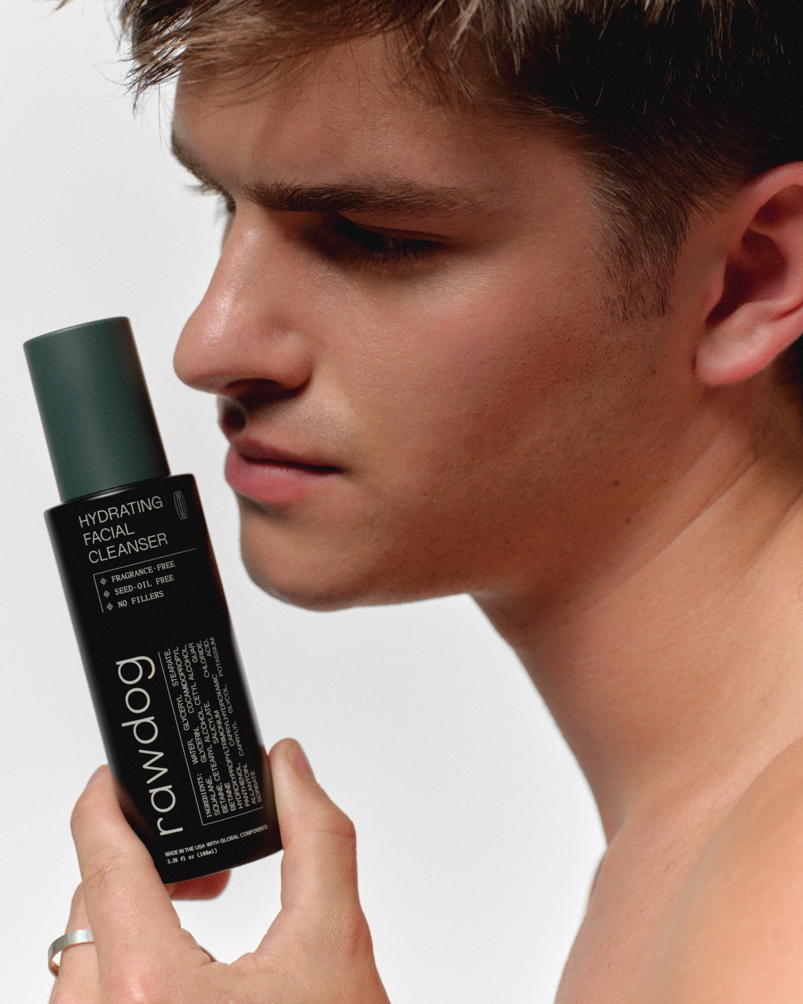 RAWDOG Hydrating Facial Cleanser held beside a man’s face