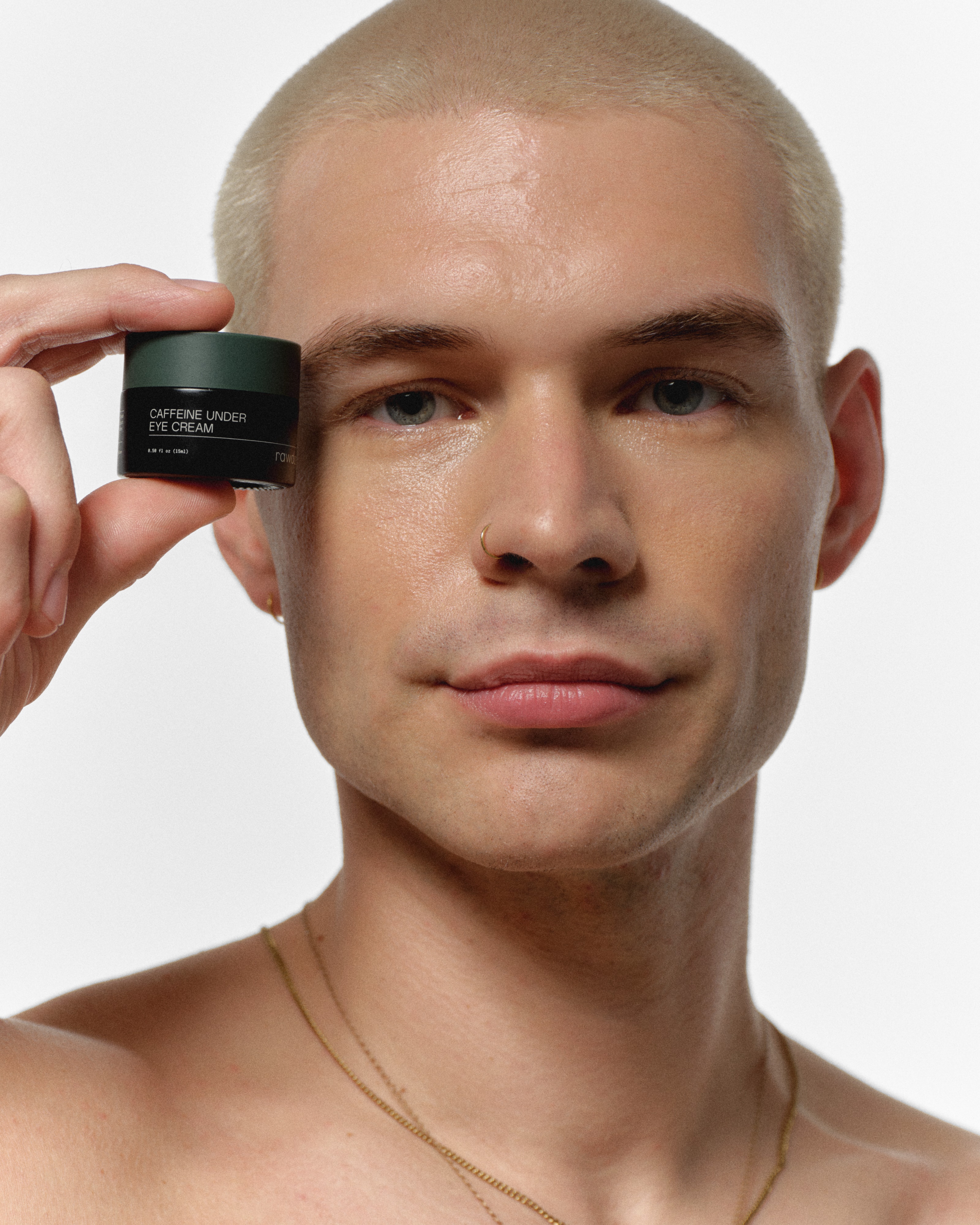 RAWDOG Caffeine Under Eye Cream held beside a man’s eye