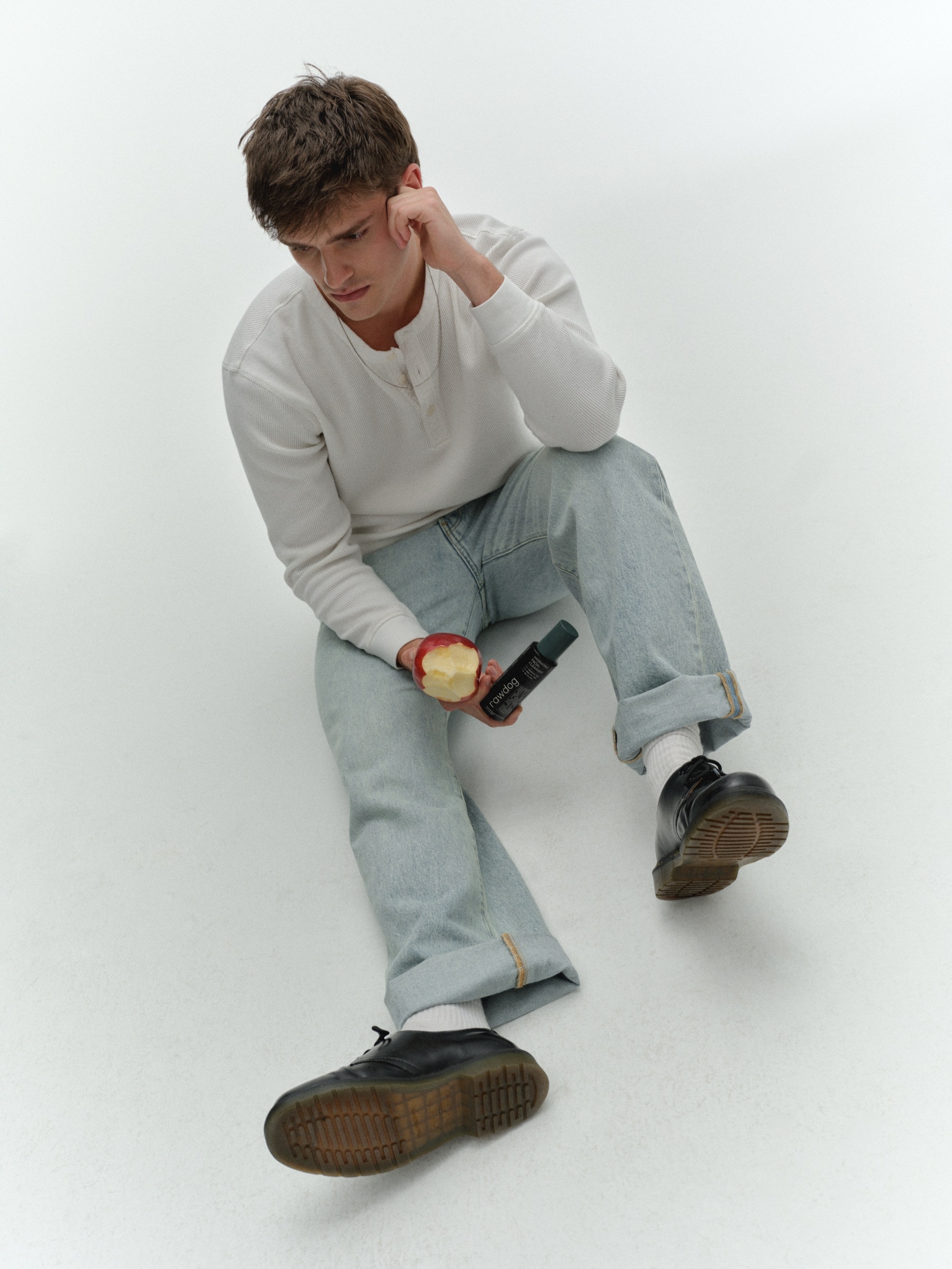 Man holding a RAWDOG cleanser and an apple